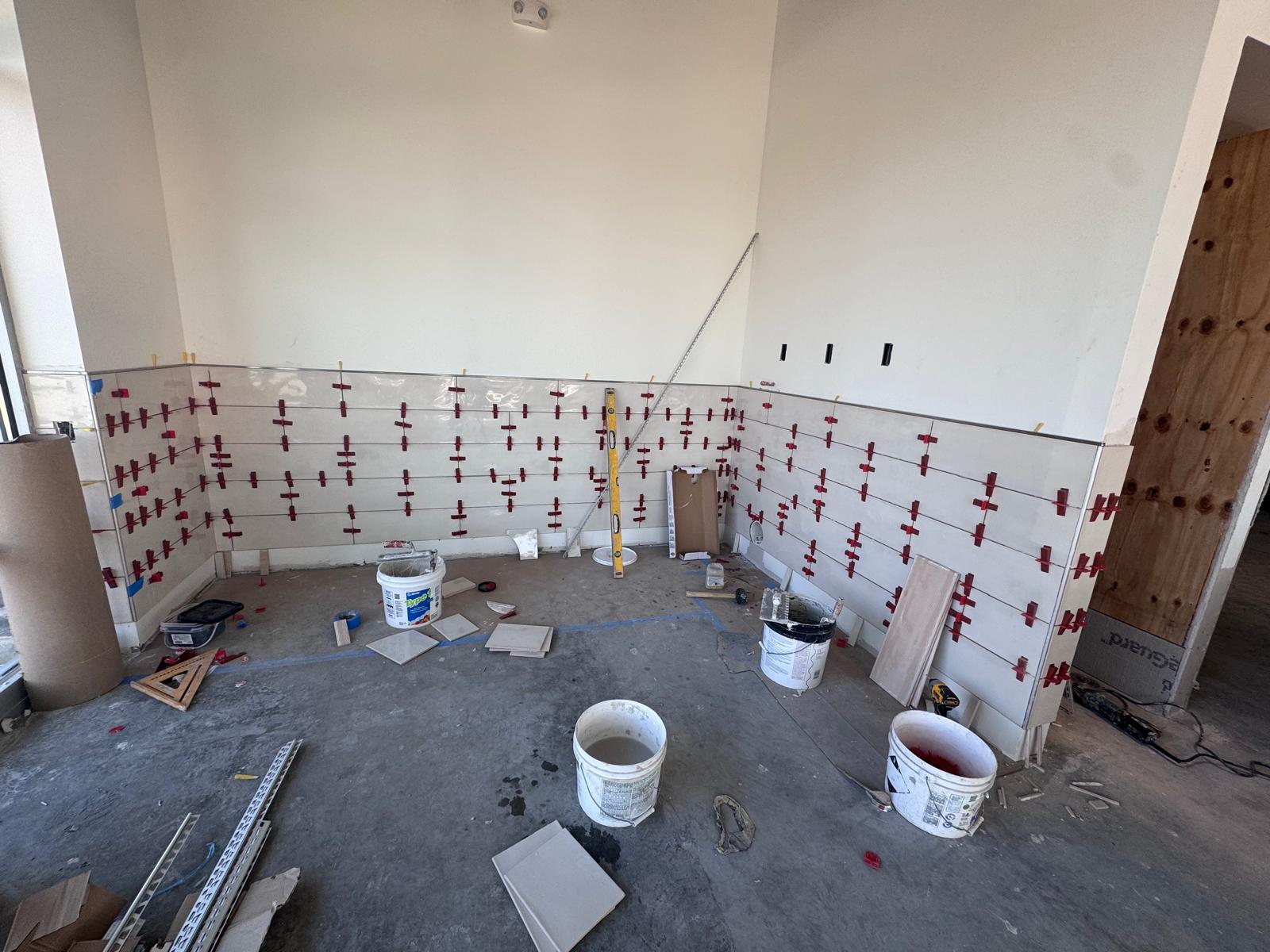 Ceramic wall tile being installed at Honeygrow Freehold, with leveling clips still in place
