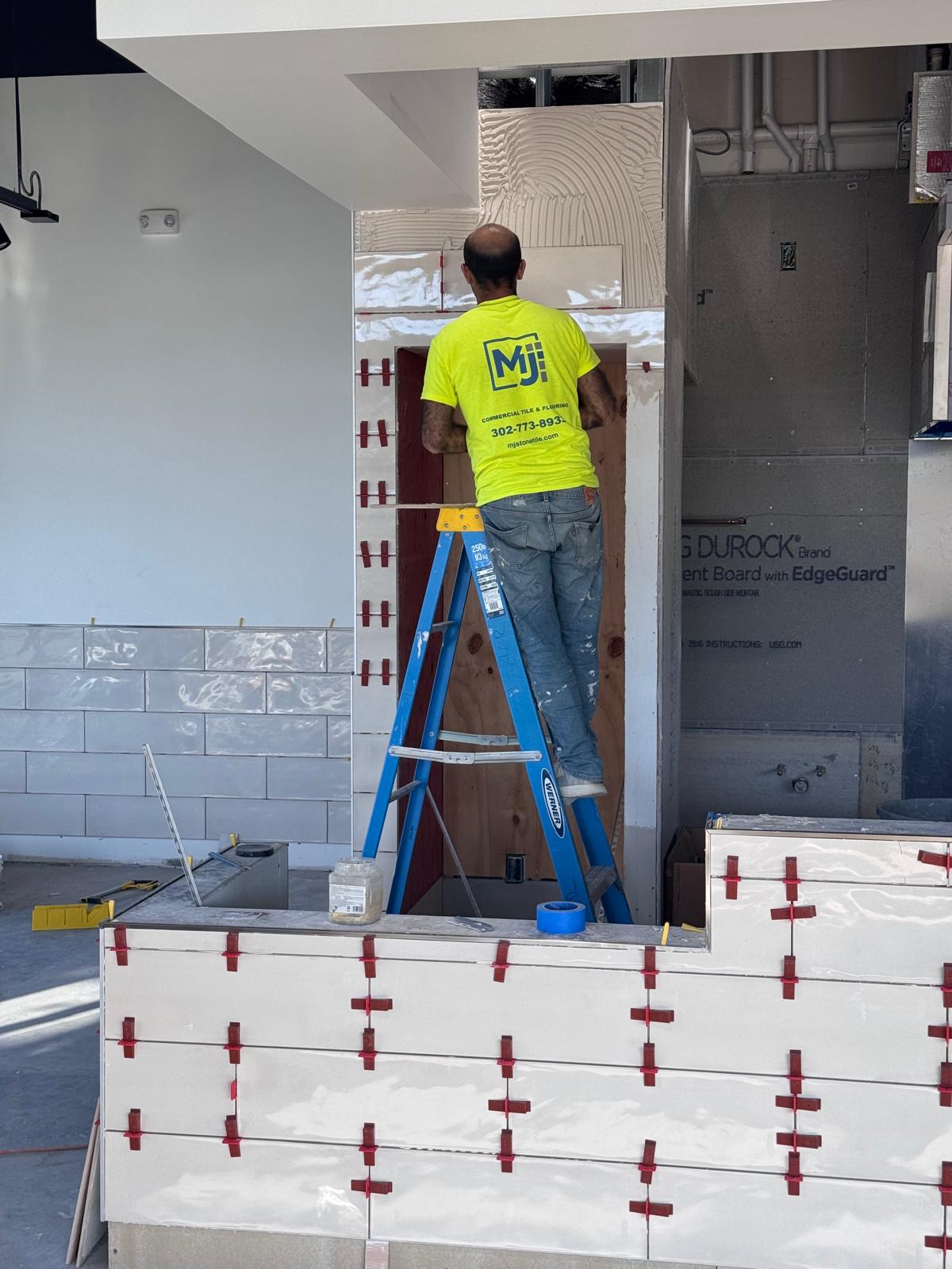 MJ Stone & Tile Works installer working on wall tile at Honeygrow Freehold