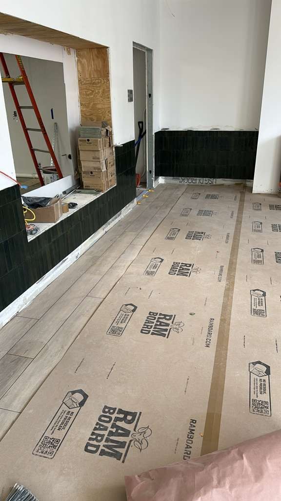 Wall and floor tile with protective floor covering during construction