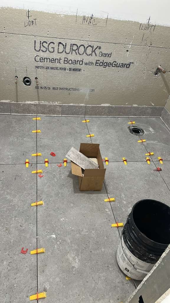 Large-format gray restroom floor tile during installation
